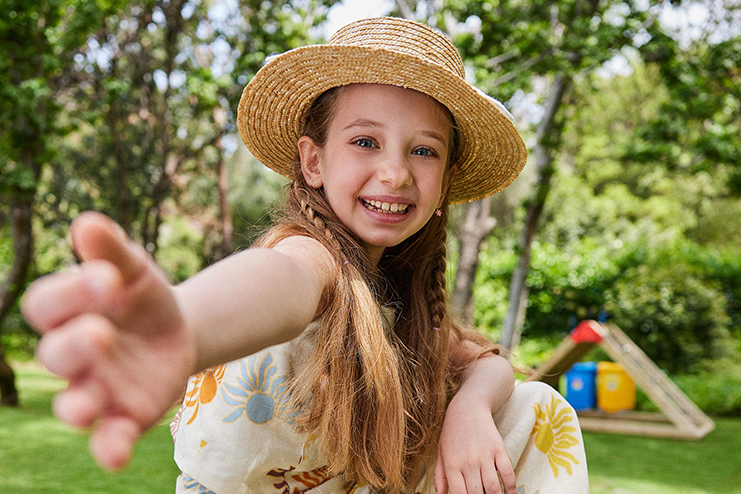 Happy girl with straw hat playing at the kids outdoor playground at D Maris Bay resort